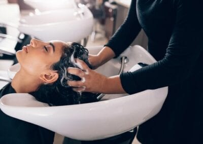 A professional hairdresser washing a customer's hair in a salon, providing a relaxing and refreshing experience. Best salon in baton rouge.
